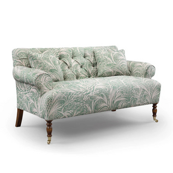 Bennett Sofa upholstered in green patterned fabric with a button-tufted back and brass castors