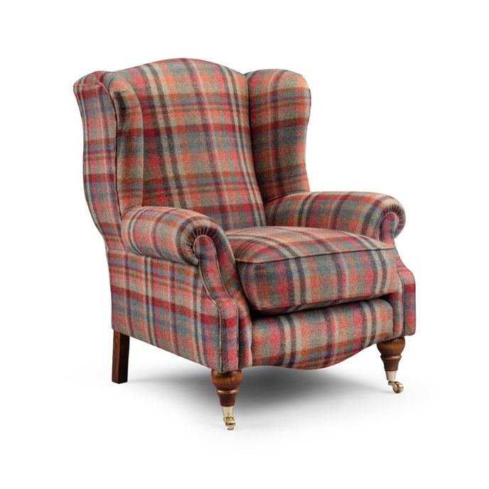 Byron Wing Chair upholstered in multicoloured plaid fabric with a high back, rolled arms, and wooden legs with brass castors