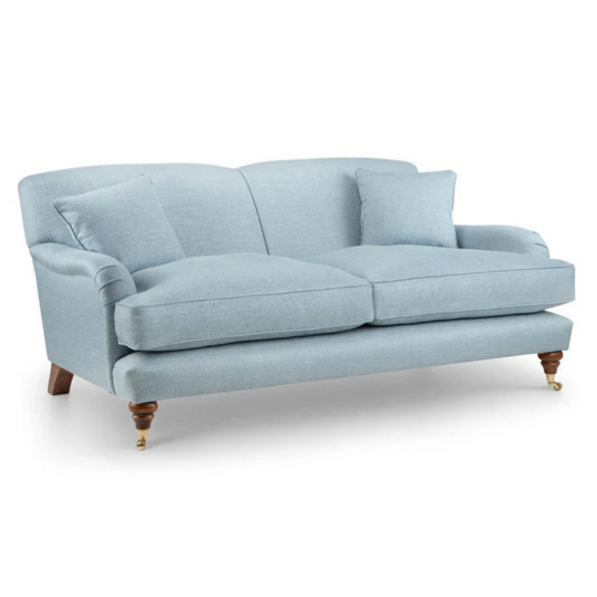 Burford Sofa upholstered in light blue fabric with rolled arms, turned wooden legs, and brass castors