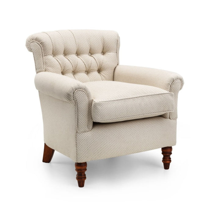 Emelia Chair upholstered in cream textured fabric with a low button-tufted back, rolled arms, and turned wooden legs