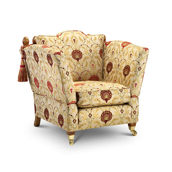 Classic Knole Chair upholstered in cream and red patterned fabric with tassel detailing and brass castors