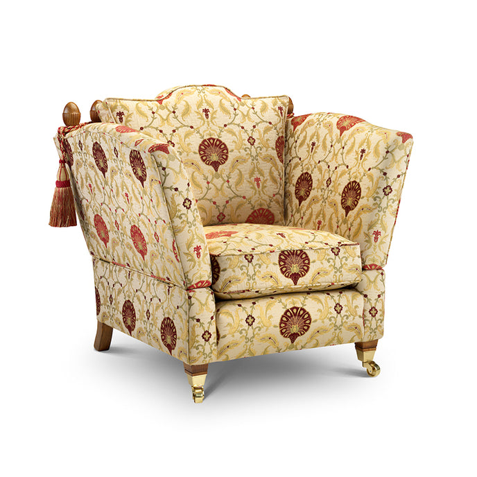 Classic Knole Chair upholstered in cream and red patterned fabric with tassel detailing and brass castors