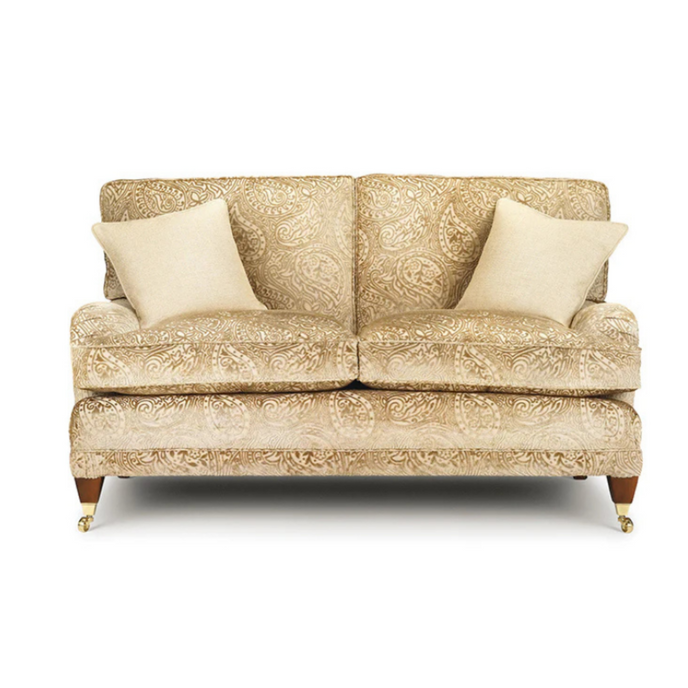Elise Sofa upholstered in beige paisley fabric with accent cushions and brass castors