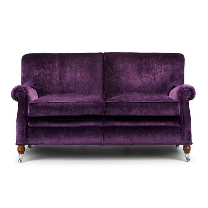 Lady Jane Sofa upholstered in deep purple velvet with rolled arms, turned wooden legs, and chrome castors