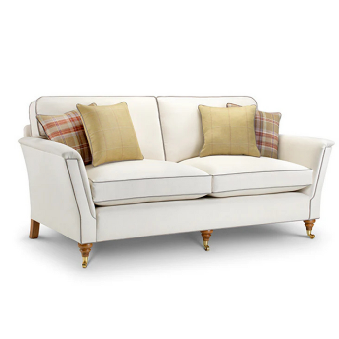 Richmond Sofa upholstered in cream fabric with contrast piping and brass castors