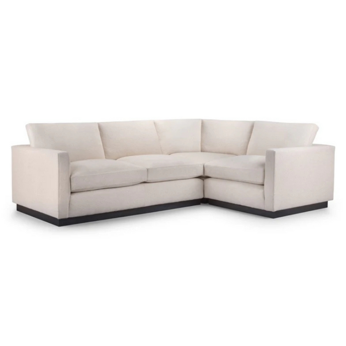 Chelsea Corner Sofa upholstered in cream fabric with angular arms and a dark plinth base
